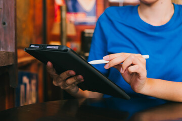 Person Using Digital Tablet with Stylus in Casual Setting at a Café for Creative Work and Daily Tasks