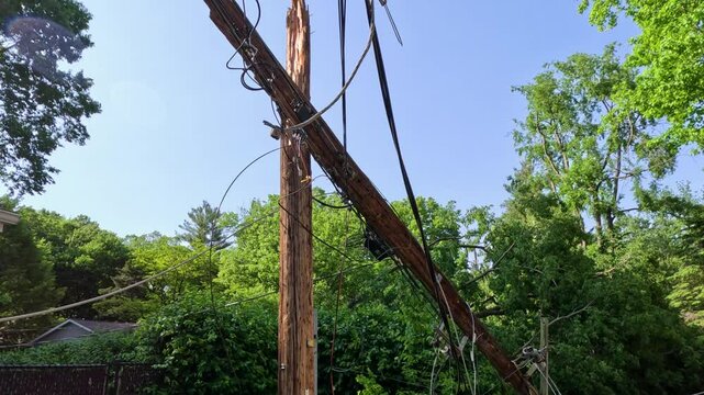 Power line completely destroyed by a fallen tree following severe storms and high winds. The wooden pole has been snapped in half created dangerous conditions and a power outage. Midwest, USA.