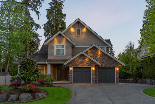 Two story stucco luxury house with nice Spring blossom landscape at night in Vancouver, Canada, North America. April 2025.