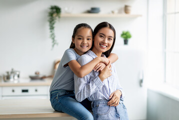 Tenderness and motherhood concept. Cute asian girl hugging young mother from the back, sitting on...