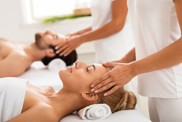 Fototapeta premium Couple Enjoying Head Massage Together, Lying On Beds With Eyes Closed At Spa Center Indoors. Wellness And Relaxation Procedure, Beauty Spa Day Concept. Selective Focus