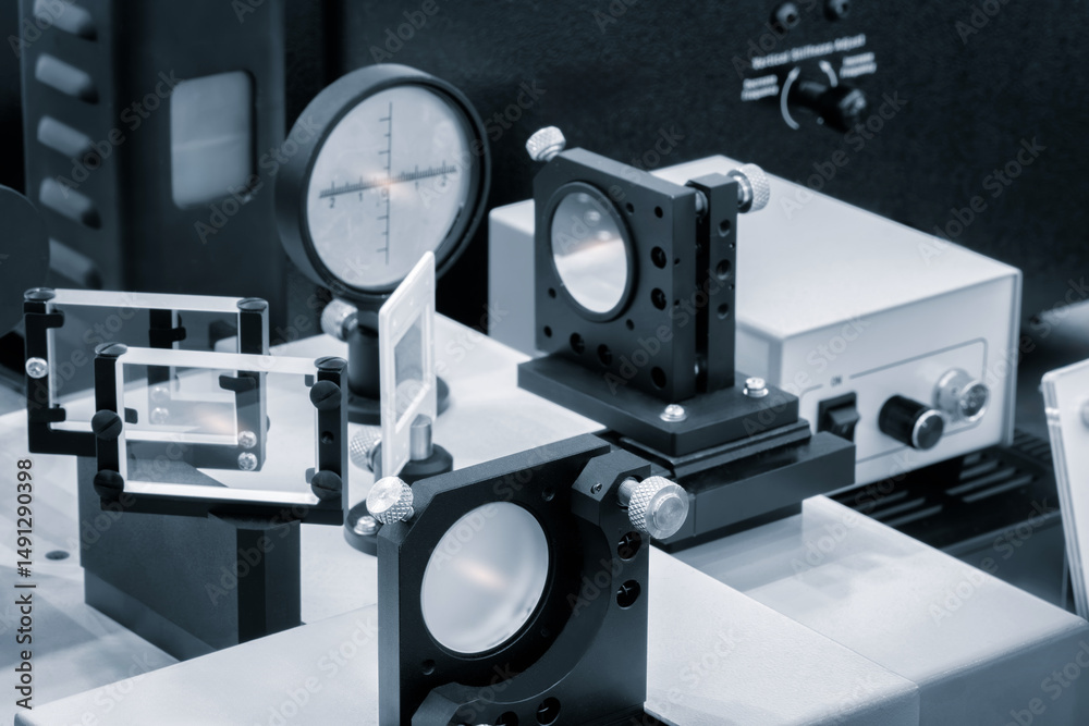 Poster Optical equipment including telescope and lenses are displayed on a table in a laboratory. Optics and photonics concept science experiment with laser background