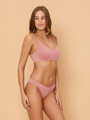 Naklejka premium Girl model in underwear posing in studio on beige background.