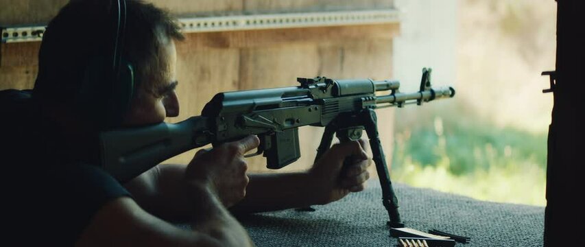 Man aims with rifle and fires a gun at outdoor shooting range during training session