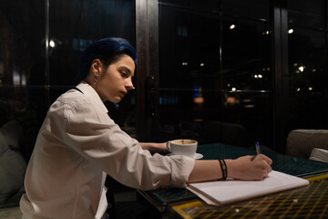 Young woman studies in evening cafe