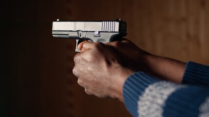 Man holding pistol enjoying recreational indoor shooting experience in firing range facility, close...