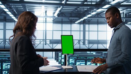 Inspector checking documents in server hub to ensure compliance with industry standards, using...