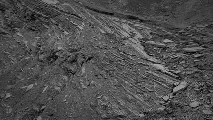 Layers and cracks in sedimentary rock on cliff face.