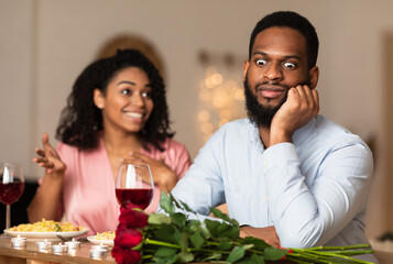 Bad First Impression And Date Concept. Dissatisfied shocked black man listening to excited emotional obsessed woman talking, young couple sitting at table in cafe. Unpleasant conversation