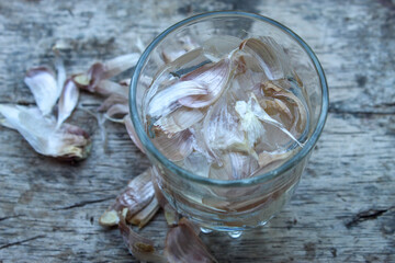 garlic skin soaked in water in a glass. the water can be used for herbs or also as a pesticide for plants