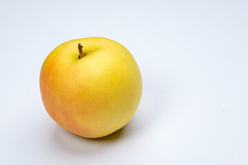 a whole flesh yellow-red orin apple  covered with small water droplet with shadow from backlight a in white background with clipping path