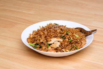 Thai style dark brown soy sauce fried rice with chicken, kale, and egg in white dish with short...
