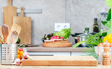 Kitchen table with cutting board, spice grinder and utensils, countertop with pans on induction hob, knives