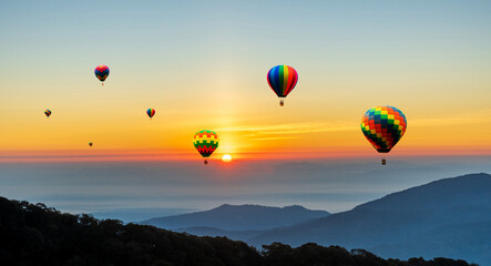 Colorful hot air balloons flying over mountain at sunset sky background
