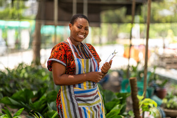 Portrait of successful African woman small business owner into horticulture standing in her garden...