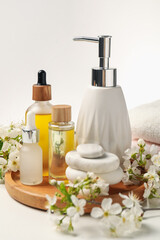 Spa products, pebble stones and twigs with beautiful flowers on white table, closeup