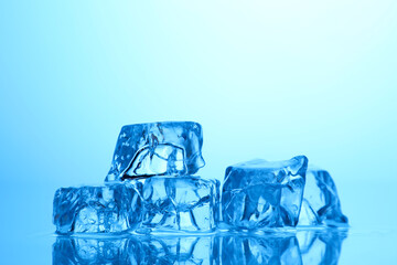 Cubes of clear ice on light blue background, closeup. Space for text