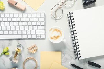 Flat lay composition with stationery, coffee and flowers on white marble table