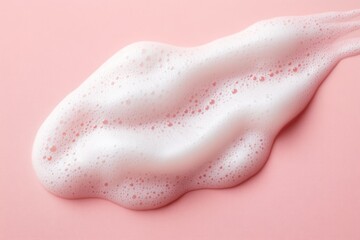Close-up of white foam or bubbles spread irregularly on smooth pink surface creating soft texture and light reflection