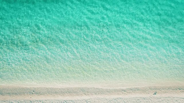 Aerial of pristine beach with gentle turquoise waves during summer in Greece