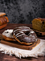 Two delicious donuts, one chocolate and the other cookies and cream on a wooden board.