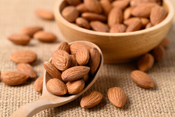 Raw almond nut seed in wooden spoon and bowl, Food ingredient