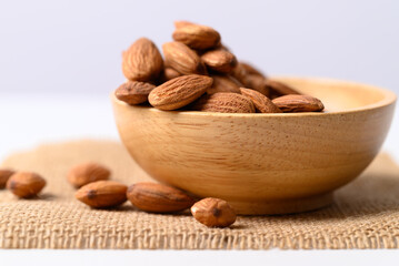 Raw almond nut seed in wooden bowl with white background, Food ingredient