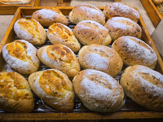 A bakery display of rustic artisan bread, featuring golden brown crusts with light flour dusting,...