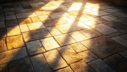 Golden sunlight streams through a window, casting elongated shadows across a stone tile floor.  The tiles are irregular in shape and size, creating a textured surface