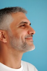 Obraz premium Visual idea art of style for aging men. Classy men's layered cut haircut - midlife middle eastern man with short hair. A modern man in his 40s with a stylish appearance. Blue solid background.