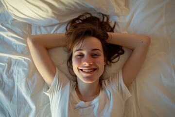 Naklejka premium A young woman lying on a bed with her hands behind her head, smiling and looking at the camera.