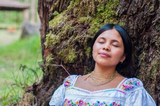 Indigenous woman resting against mossy tree in guatemala, enjoying nature's embrace