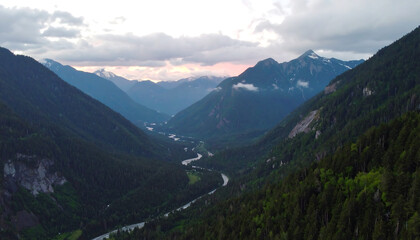 Obraz premium Majestic Alpine Mountain Range with Verdant Valleys and Flowing River