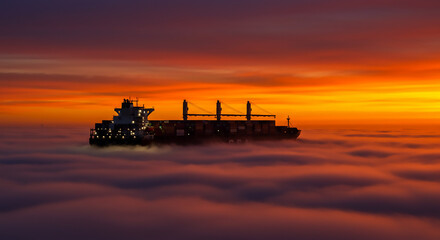 A cargo ship sailing on a sea of clouds during a vibrant orange and purple sunset sky horizon view