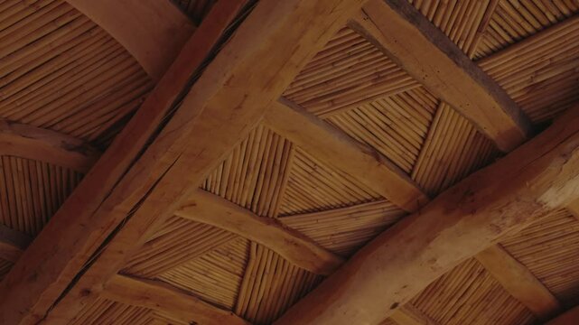 Close up of a beautiful wooden and bamboo ceiling with an intricate geometric pattern. The warm tones of the wood and the craftsmanship create a cozy, ambiance. architecture, interior design,