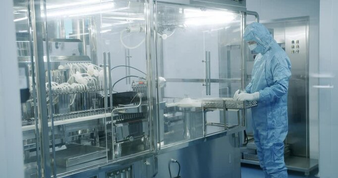 Sterile Pharmaceutical Manufacturing Laboratory where Scientists in Protective Coveralls. Factory Cleanroom. Pharmaceutical, Biotechnological and Semiconductor Creating Manufacturing Process.