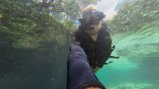 Over-Under water selfie: Man snorkels in clear river water current