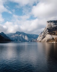 Obraz premium Serene Lake Traunsee in Austria Surrounded by Majestic Mountains and Dramatic Clouds Scenic Landscape View