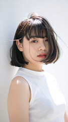 Fototapeta premium Modern portrait of a woman with a blurred face showcasing a sleek bob haircut and white sleeveless top capturing contemporary fashion