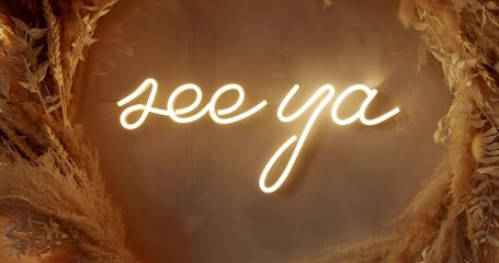Warm, inviting neon sign spells See Ya surrounded by a rustic wreath. Conveys feelings of goodbye, farewell, departure, or the end of an event or experience. Ideal for social media