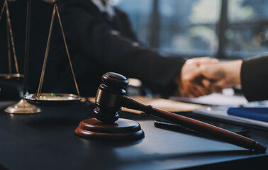 Two lawyers shaking hands after reaching an agreement during a legal trial, with scales of justice and gavel in the foreground