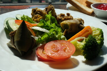 on a plate tomatoes broccoli chicken salad and vietnamese triangle palm leaves breakfast at the hotel
