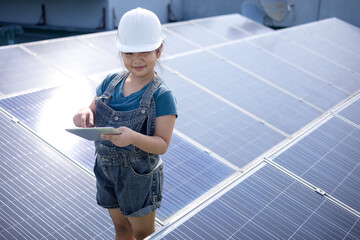 Girl wearing white engineer hat holding tablet standing with solar panel