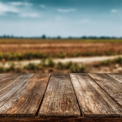 Rustic wooden table surface with blurred farmland background in a rural landscape setting under blue sky