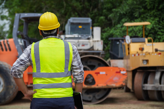 Back view of construction workers watching an excavator operate at a busy worksite, capturing teamwork, machinery, and industrial atmosphere.