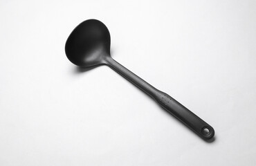 Black plastic kitchen ladle on white background