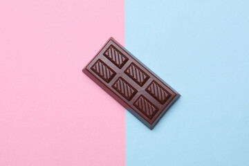 Toy plastic chocolate bar on blue pink background. Top view