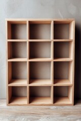 Empty wooden shelf unit on wood floor against gray wall in studio shot for product display or organization storage solution