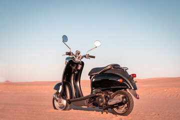 Stylish black retro scooter in the Namib Desert at sunset. Perfect for travel, adventure, freedom, and vintage lifestyle themes