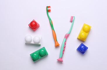 Children's plastic toothbrushes with toy bricks on a white background
